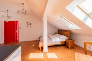 比亚韦斯托克Kamienica Zamenhofa - Apartamenty na wynajem的阁楼卧室设有一张床和一扇红色的门