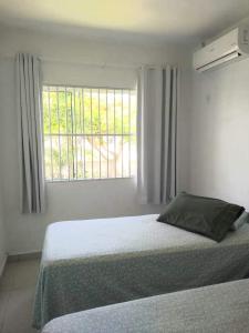 加罗帕巴Casa de praia na Gamboa - Garopaba SC的白色的卧室设有床和窗户