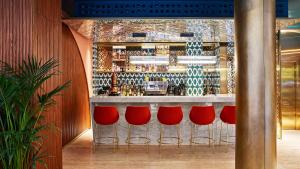 巴塞罗那Kimpton Vividora Hotel, an IHG Hotel的吧台前有红色凳子的酒吧