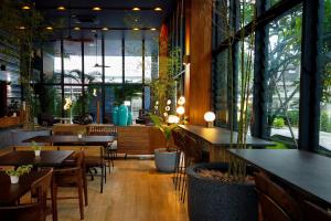华欣Seamira House Huahin - SHA的餐厅设有桌椅和大窗户。