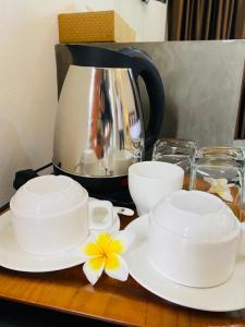 Ban Bo ThongDark Sugar Resort的桌子上放两个白杯和碟子,配有咖啡壶