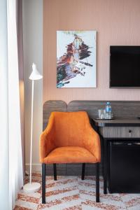 考纳斯考那斯酒店的一张橙色椅子,放在带书桌的房间