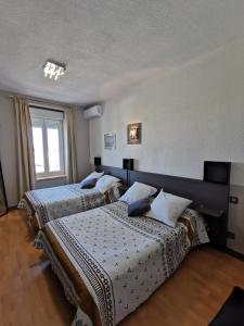 拉努韦勒港l'Hotel du port的一间卧室设有两张床和窗户。