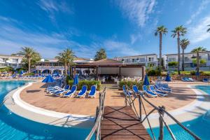 松霍里吉尔Sagitario Princesa Playa的度假村的游泳池,设有蓝色的椅子和棕榈树