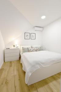 特伦钦Apartmán s átriom v historickom centre的白色卧室设有白色的床和木地板