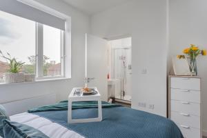 斯蒂夫尼奇Luxury Serviced Apartments Stevenage, Hertfordshire的白色卧室配有床和桌子