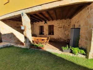 卡米诺新村Casa Rural El Caño de Abajo的石头建筑下方的庭院配有桌椅