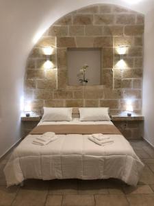 奥斯图尼Casetta dello Scrittore的一间卧室设有一张带石墙的大床