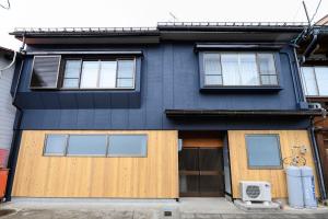 高山BEYOND HOTEL Takayama 4th - Vacation STAY 99852的蓝色的房子,设有木门和窗户
