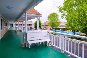 奥尔良Rodeway Inn Orleans - Cape Cod的游泳池旁带长凳的门廊