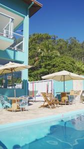 圣塞巴斯蒂安Residencial Águas de Bare的一组椅子和遮阳伞,位于游泳池旁