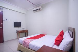 黑风洞Super OYO 89363 Casavilla Hotel的一间卧室配有一张带红色枕头的床和一张桌子