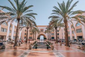 马斯喀特Shangri-La Al Husn, Muscat - Adults Only Resort的庭院里种有棕榈树,设有喷泉