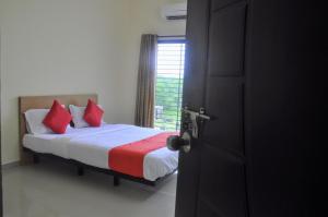那格浦尔Hotel Relax Inn的一间卧室配有一张带红色枕头的床和一扇窗户