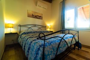 圣塔·马里亚·迪·帕尔玛Bonsai B&B Alghero的一间卧室配有一张带蓝色棉被的床和窗户。
