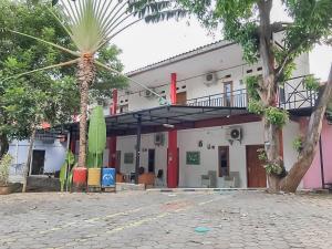井里汶Rumah Panggung Guest House Syariah Mitra RedDoorz的前面有棕榈树的建筑