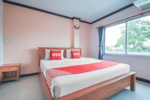 洛坤府OYO 1145 Prickhom Garden Hotel的一间卧室配有一张带红色枕头的床和一扇窗户