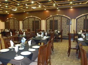 锡亚尔科特Hotel de Raj Sialkot的一间在房间内配有桌椅的餐厅