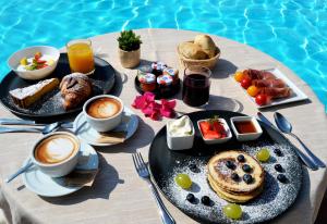 圣玛格利特迪普拉迪菲奥里海岸酒店的桌边的桌边,桌边摆着早餐食品和饮料