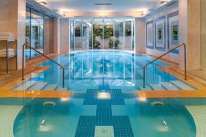 雅典Holiday Inn Athens Attica Av, Airport W., an IHG Hotel的游泳池设有蓝色瓷砖地板和窗户