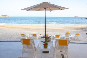 圣克鲁斯华特库Hotel Castillo Huatulco & Beach Club的海滩上的桌椅和遮阳伞