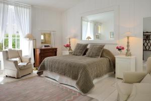 圣马丹德雷La Baronnie Hôtel & Spa - Teritoria的一间卧室配有一张床、一把椅子和镜子