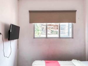 巴图RedDoorz near Eco Green Park Batu的一间卧室设有窗户、一张床和一台电视机
