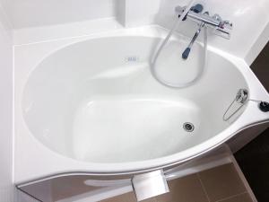 广岛KOKO HOTEL Hiroshima Ekimae的浴室内设有带水龙头的白色浴缸