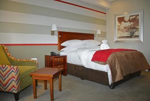 哈博罗内Indaba Lodge Gaborone的配有一张床和一把椅子的酒店客房