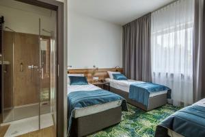 拉辛Bloom Hotel Airport Okęcie的酒店客房设有两张床和淋浴。