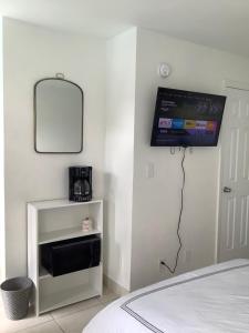 劳德代尔堡Hotel Motel Lauderdale Inn的卧室在床边的墙上配有电视
