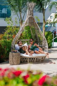 帕福斯Sofianna Resort & Spa的两个男人躺在海滩上的吊床上