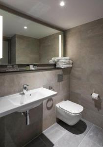 格拉斯哥Maldron Hotel Glasgow City的一间带水槽、卫生间和镜子的浴室