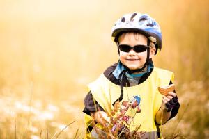 福堡福堡峡湾酒店的一名穿着自行车头盔和太阳镜的年轻男孩吃食物