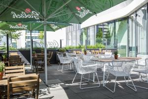 阿姆斯特丹竞技场塔阿姆斯特丹假日酒店的一间带桌椅和绿色遮阳伞的餐厅