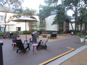 欧文Holiday Inn Irving Las Colinas, an IHG Hotel的庭院配有桌椅和遮阳伞。