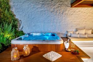 罗希姆诺Vista Del Porto Luxury Suites的一个带桌子的客房内的按摩浴缸