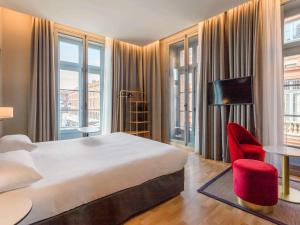 图卢兹宜必思风格图卢兹卡皮托勒酒店的酒店客房带大床和红色椅子