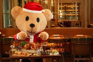 苏州苏州园区香格里拉的戴着桑塔帽的泰迪熊站在餐桌旁吃着东西
