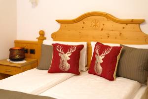 卡纳泽伊Hotel il Caminetto Sport的一张带两个红色枕头的床,上面有鹿头