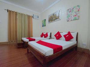 公主港OYO 658 Roccksar Pension的一间卧室配有两张带红色枕头的床