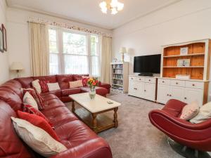 托基Babbacombe Hall的客厅配有红色皮革沙发和椅子