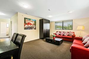 基督城Quality Suites Amore的客厅配有红色的沙发和桌子