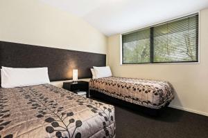 基督城Quality Suites Amore的一间卧室设有两张床和窗户。