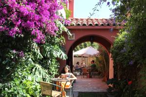 拉塞雷纳El Arbol Hostel的坐在花朵紫色的花园桌子上的女人