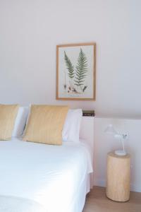 TivissaHotel Rural Mas de l'Illa的卧室配有白色的床,墙上挂着一幅画