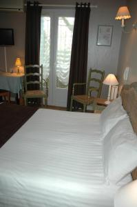 拉康提内勒Hôtel L'Ecailler的一张大白色的床,位于带椅子的房间