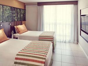 新伊瓜苏Mercure Rio de Janeiro Nova Iguaçu的酒店客房设有两张床和窗户。