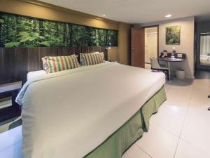 新伊瓜苏Mercure Rio de Janeiro Nova Iguaçu的一张大白色的床,位于带书桌的房间里