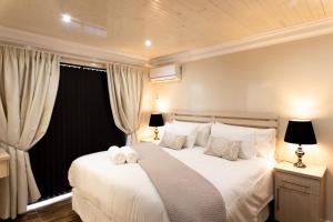 杰弗里湾Grand House Lodge And SPA Jeffreys Bay的卧室配有白色的床和2条毛巾